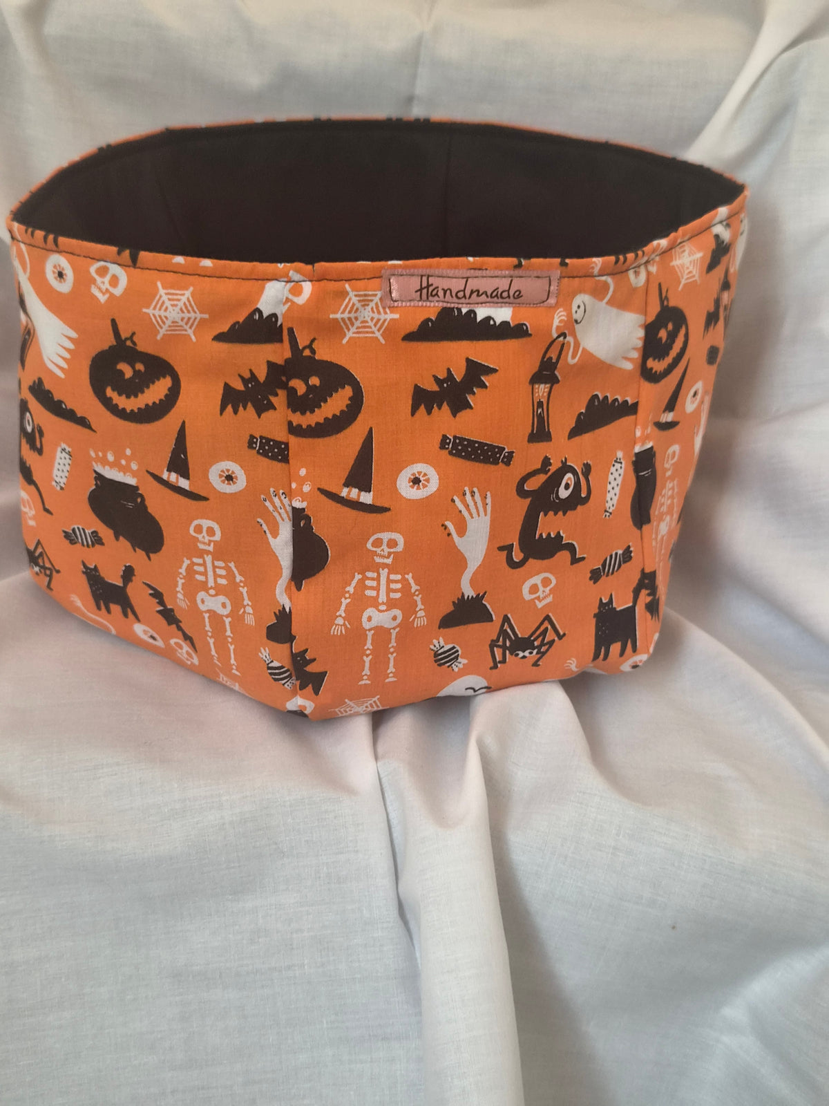 Handmade Halloween fabric basket with pumpkins, skeletons and bats on orange fabric